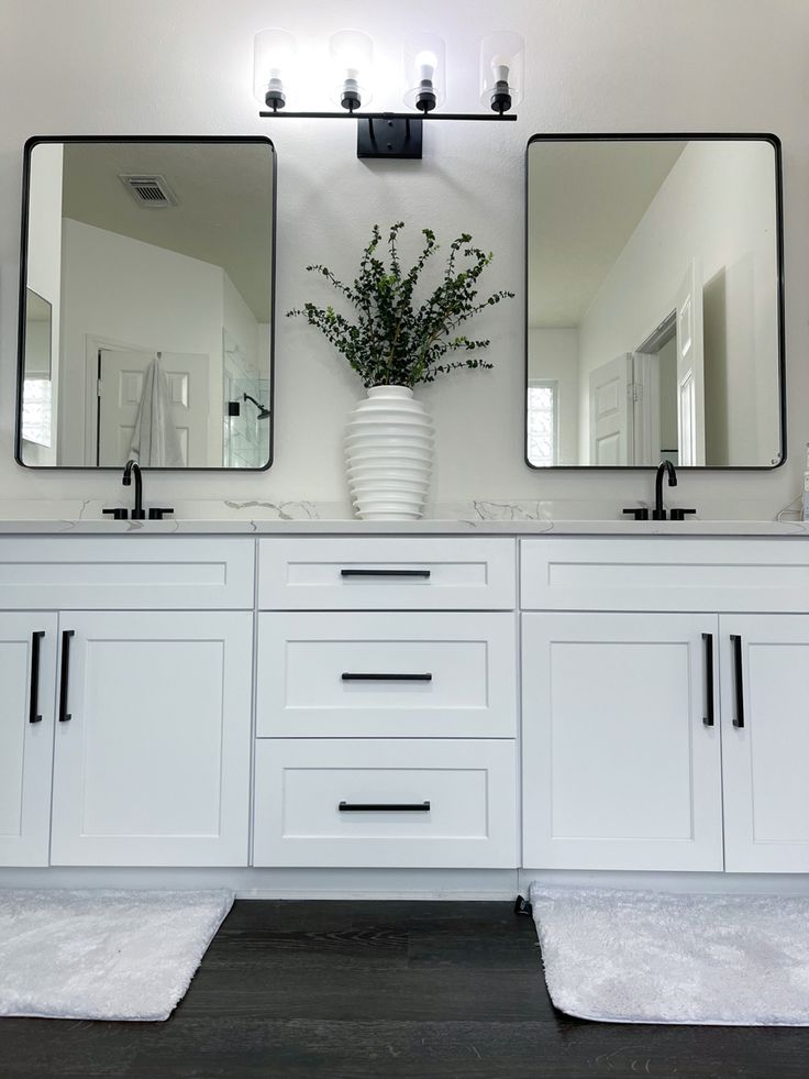 a bathroom with two sinks, mirrors and rugs in front of the sink area