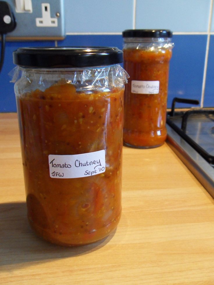 two jars of food sitting on top of a wooden counter next to a stovetop