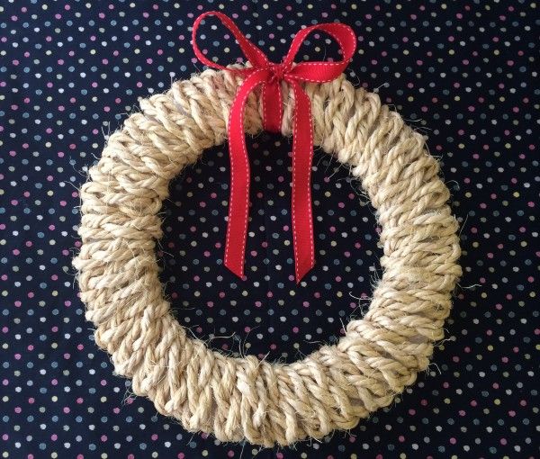 a rope wreath with a red bow hanging on a polka dot tablecloth covered wall