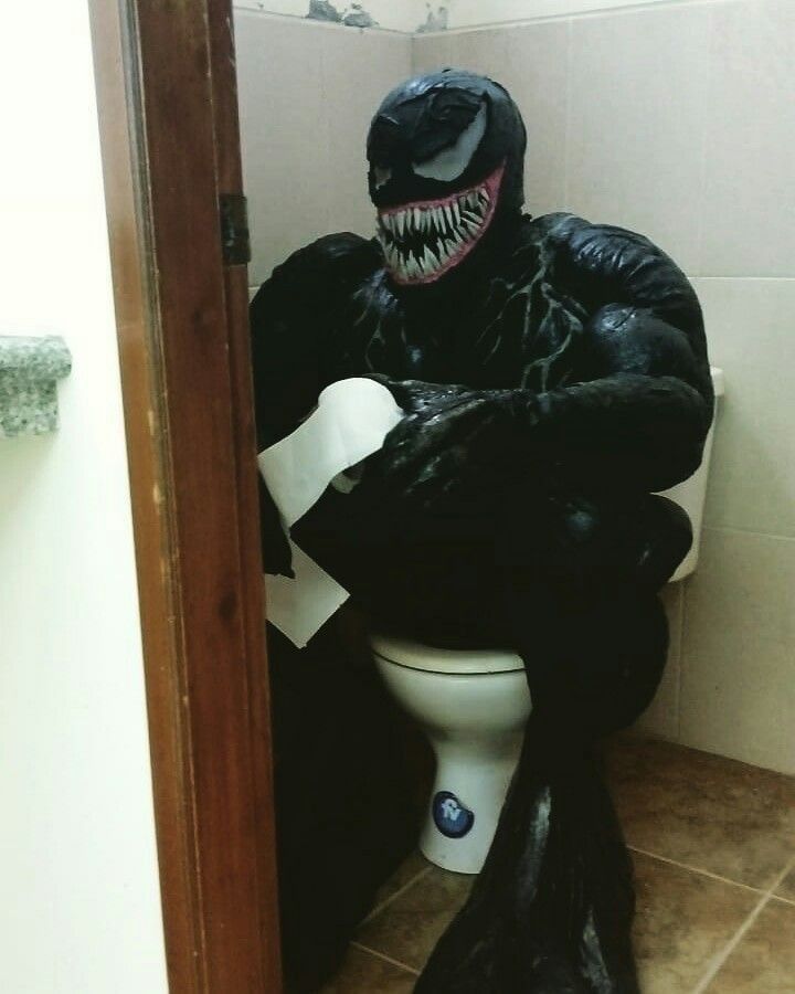 a toilet that has a monster on the top of it, in a bathroom with tile flooring and walls