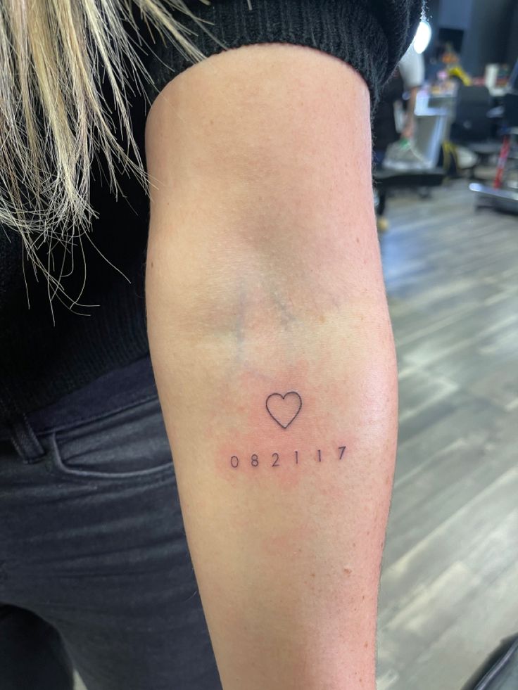 a woman's arm with a small heart tattoo on the left side of her arm