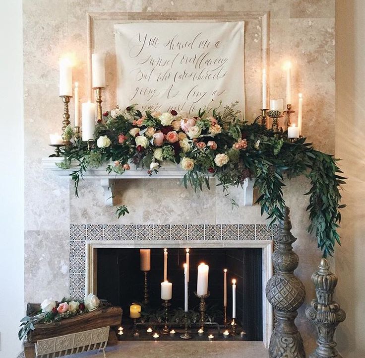 the fireplace is decorated with flowers and candles for an elegant touch to the mantel