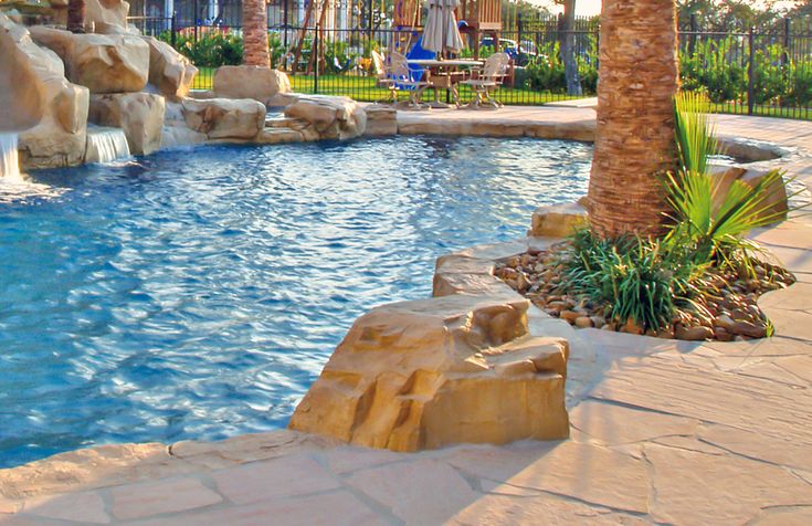 an outdoor pool with waterfall and palm trees