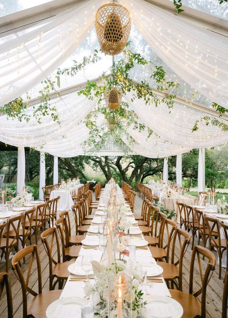 an outdoor tent with tables and chairs set up for a formal dinner or wedding reception