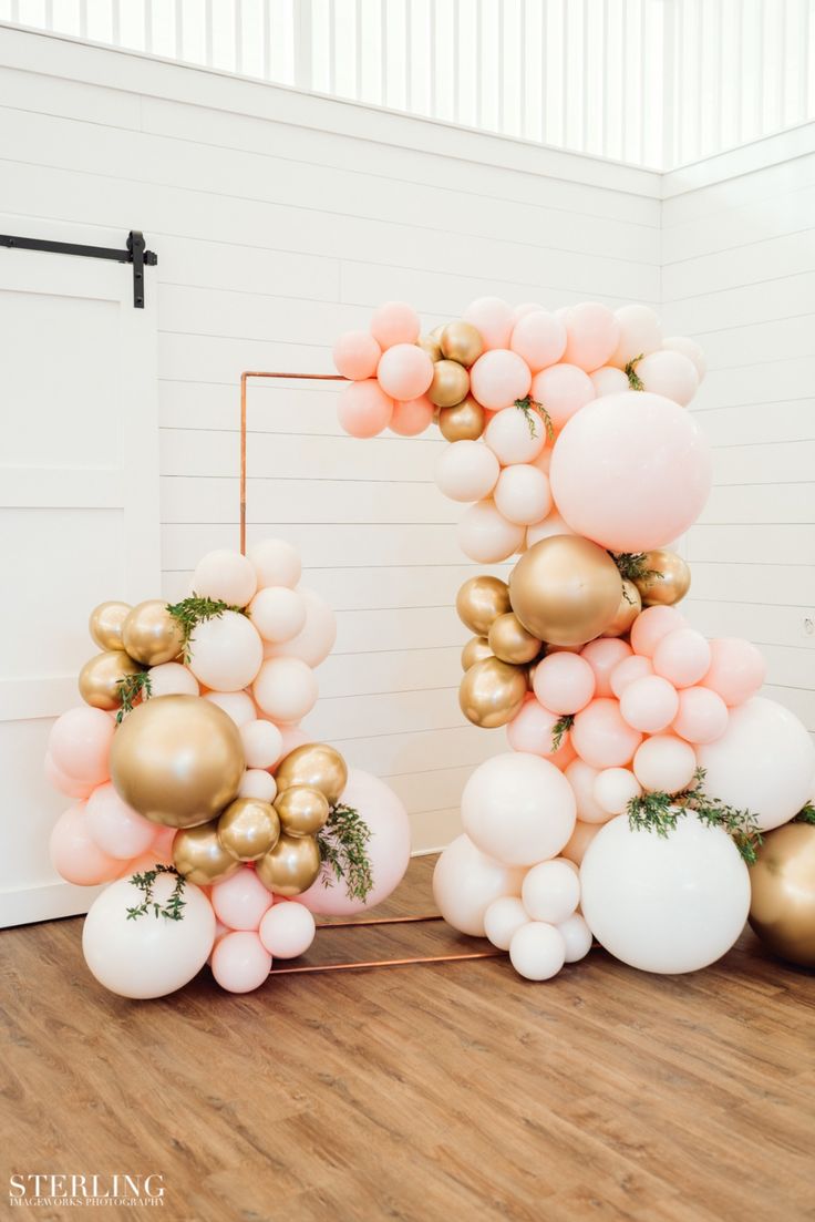 the balloon letter is made up of gold and white balloons with greenery on top