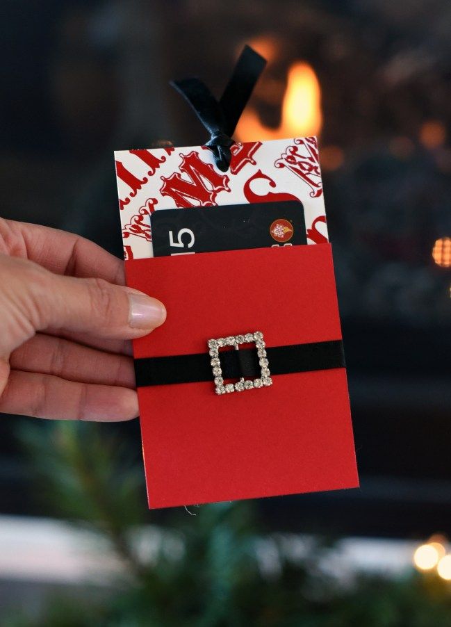 a hand holding a red and black card with a christmas ornament on it