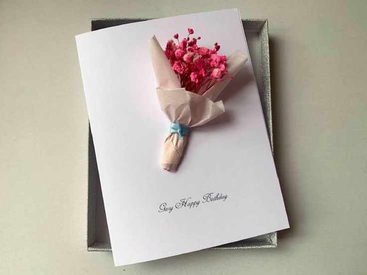 a bouquet of pink flowers sitting on top of a white greeting card in a box