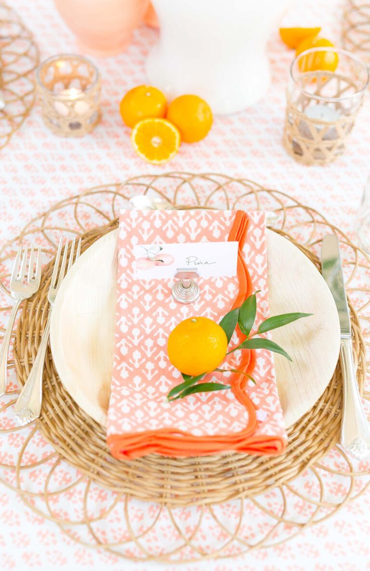 a place setting with oranges and napkins