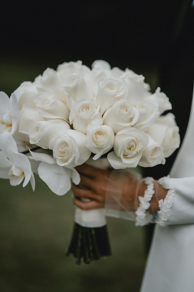 a bride holding a bouquet of white roses