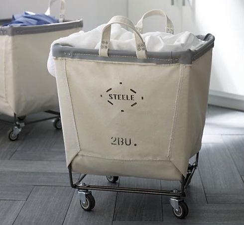 a white shopping bag sitting on top of a hard wood floor next to a trash can