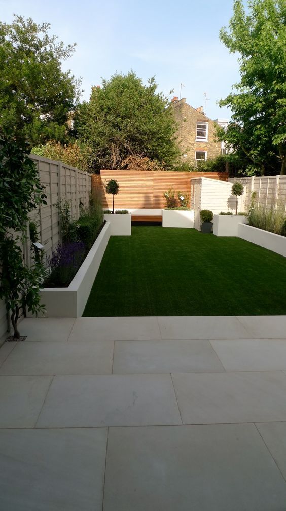 an outdoor garden with grass and white walls