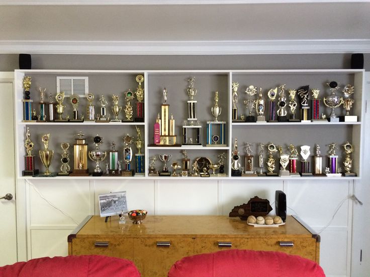 two red chairs sitting in front of a book shelf filled with trophies