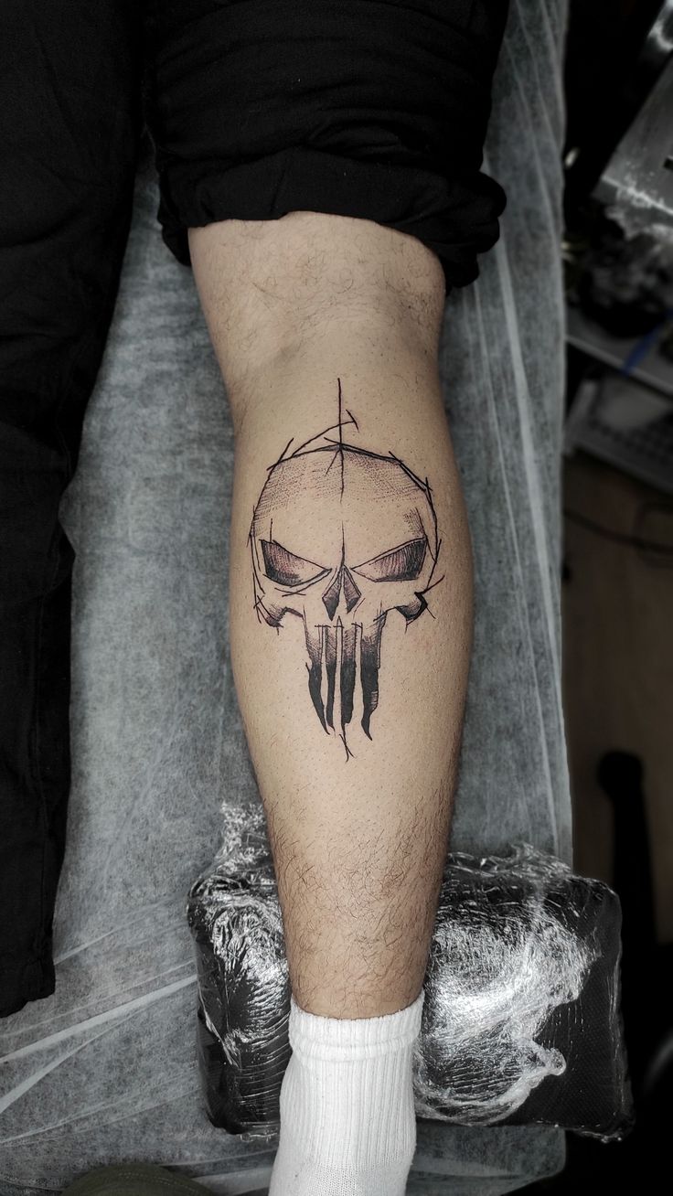 a man's leg with a tattoo on it that has a skull in the middle