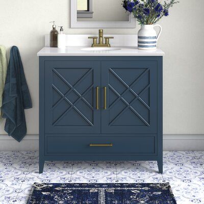 a bathroom vanity with a blue cabinet next to a mirror and rug on the floor