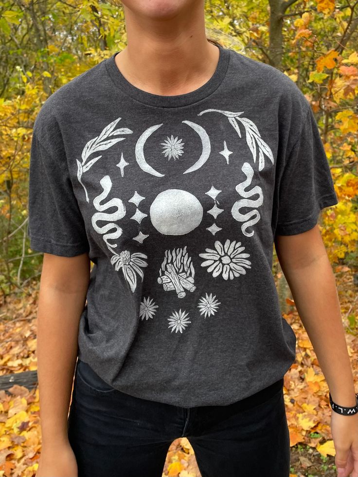 A secondhand T-Shirt with a block-printed design! This Full Moon Design was created with ceremony in mind - wear this shirt near the full moon or when you need some extra full moon energy in your daily life (or if you just want to look very cute with very little effort). This design is offered in other sizes and colors - please see my Etsy page for more offerings! My mission is to bring sacred ceremony into daily life. By curating secondhand clothes and adding symbolism with intention, I hope to spread some love of nature, the Divine, and simple beauty back into all our lives. Each piece I offer was thrifted and chosen with care, lovingly block-printed with hand-carved stamps, and shared with you in community.  My process usually goes a little something like this: Inspiration from nature, Mystical Cotton Crew Neck T-shirt, Bohemian Short Sleeve T-shirt With Sun And Moon Design, Bohemian Cotton T-shirt With Sun And Moon Design, Festival T-shirt With Screen Print And Relaxed Fit, Cotton Graphic Tee With Moon Print, Mystical Crew Neck Cotton T-shirt, Mystical Style Cotton T-shirt With Crew Neck, Mystical Style Cotton Crew Neck T-shirt, Mystical Short Sleeve Top With Graphic Print