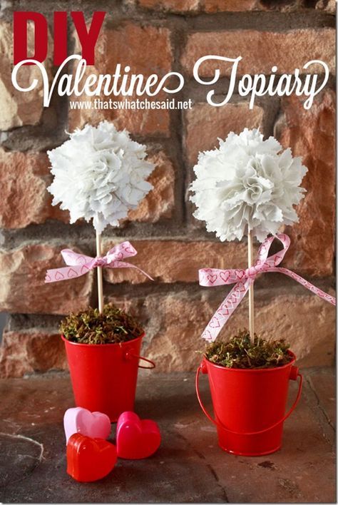 two red buckets filled with white flowers and pink hearts sitting next to each other