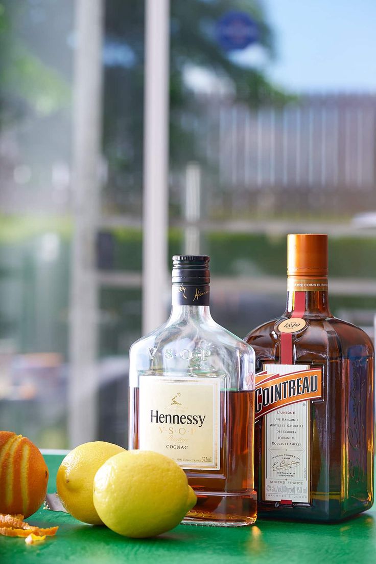 bottles of alcohol and lemons sit on a counter top next to an orange peel