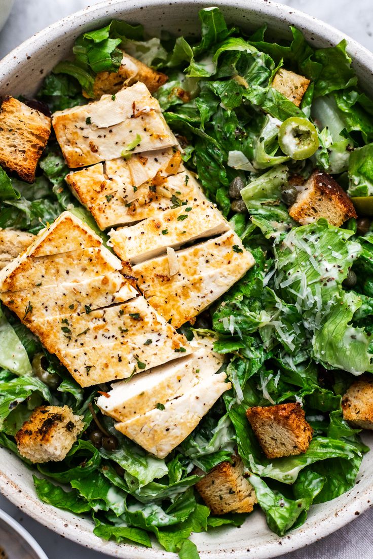 a salad with tofu and lettuce in a white bowl on a table