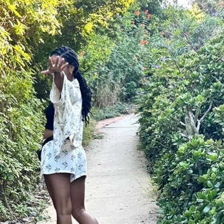 a woman is walking down a path in the woods with her hand up to her mouth