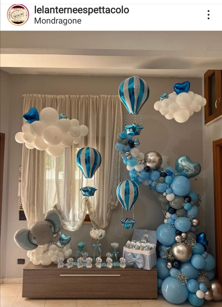 balloons and other decorations are displayed on the wall in this blue and white theme for a baby's first birthday