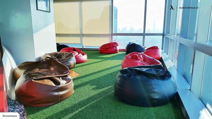 bean bag chairs are lined up on the green carpeted floor in an office building