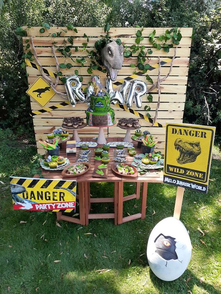 a table set up in the grass with signs and decorations on it for an animal themed birthday party