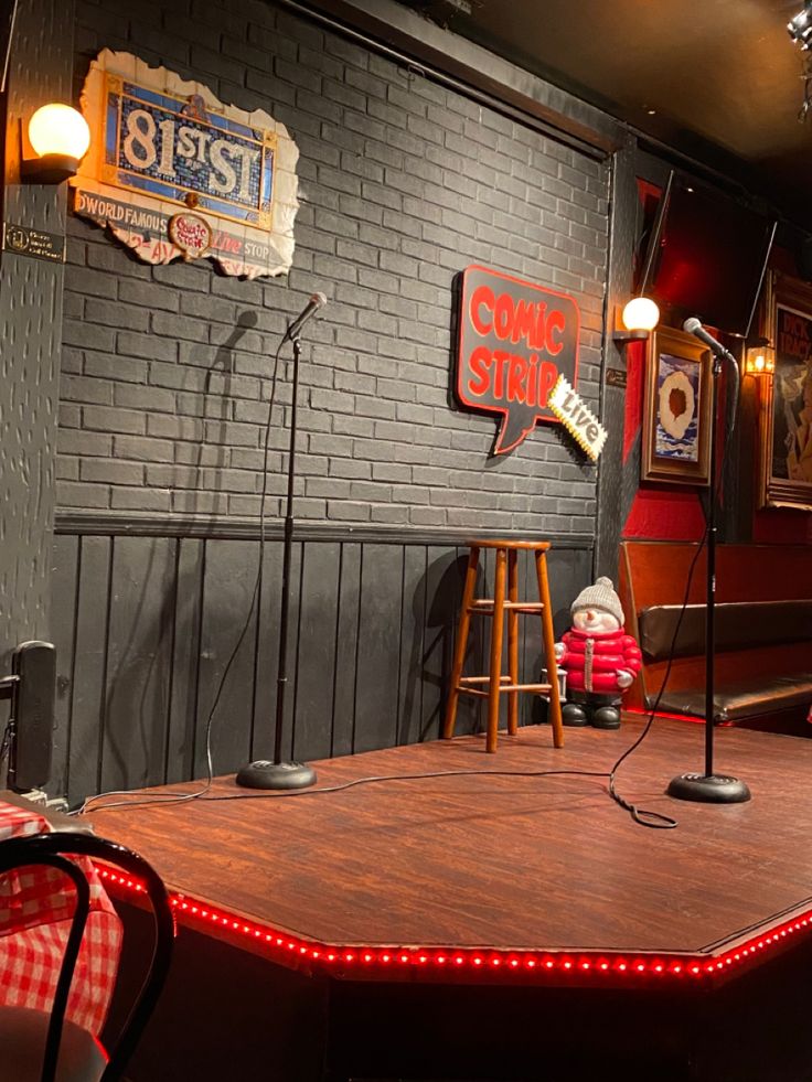 a table with two microphones on it in front of a brick wall and chairs