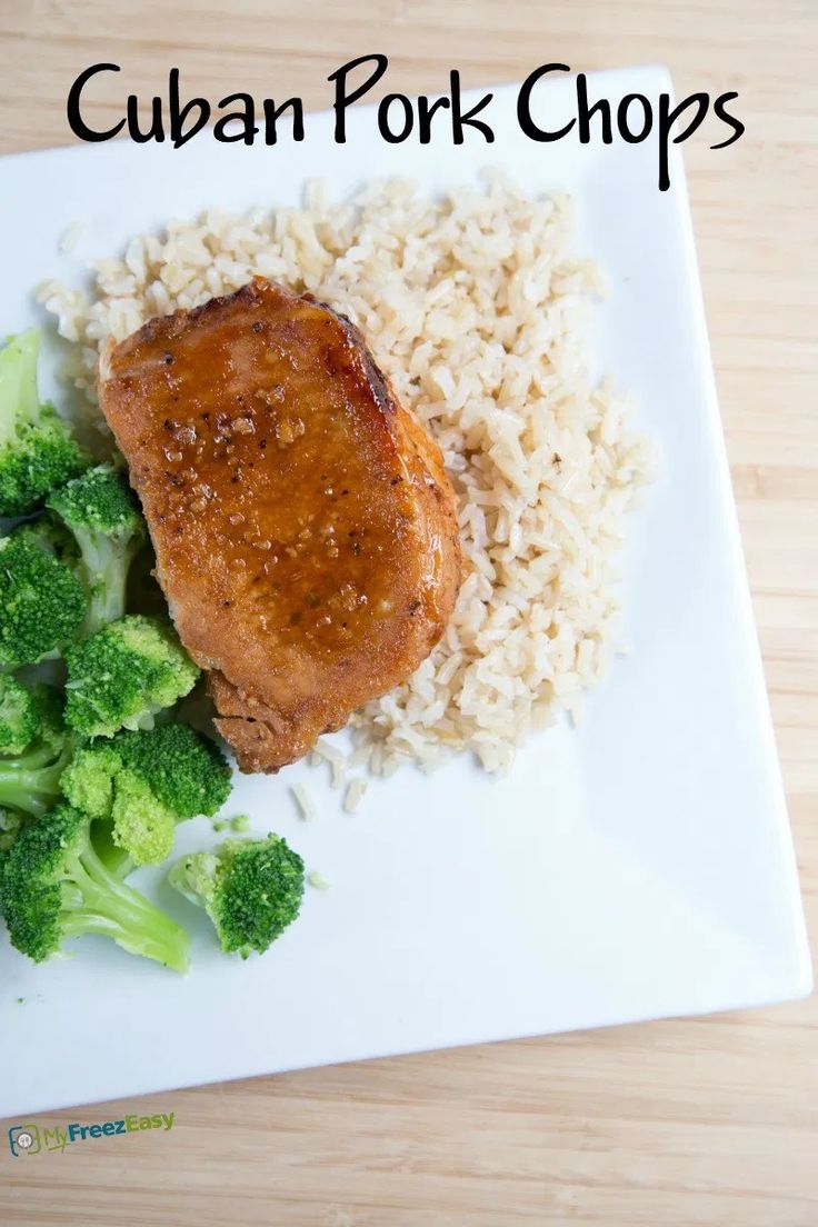 a white plate topped with meat and rice next to broccoli on a wooden table