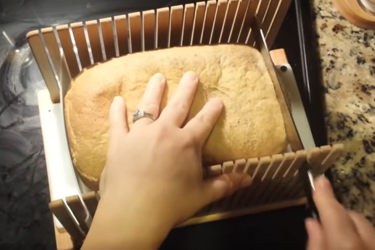 a person is using a knife to cut bread