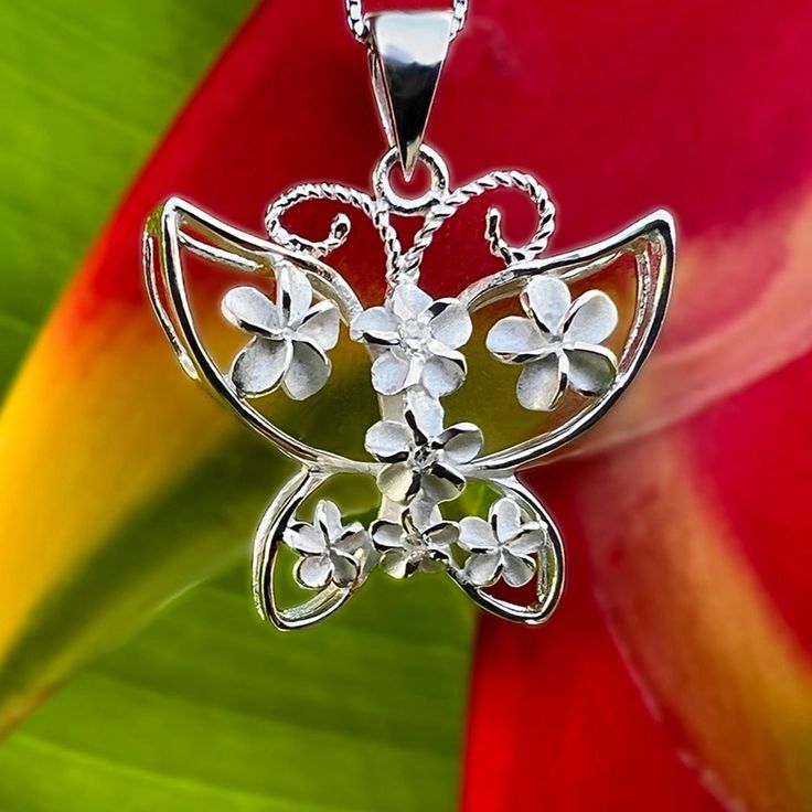 Butterflies and Flowers go hand in hand so we created our beautiful Plumeria Butterfly Pendant with that in mind! Our three dimensional butterfly is accented with Plumeria flowers throughout. Down the center of the pendant the flowers have little cubic zirconia stones that add that extra bling. Includes an 18” adjustable chain. Crafted from .925 Sterling Silver. .925 Sterling Silver Cubic Zirconias 3D Design Includes 18" Adjustable Chain Size Approximately 1" x 1" Flower-shaped Butterfly Charm Jewelry Gift, Flower Butterfly Charm Jewelry Gift, Flower Shaped Butterfly Charm Jewelry Gift, Flower Shaped Butterfly Charm Jewelry As Gift, White Butterfly Necklace For Wedding, White Sterling Silver Butterfly Necklace, Silver Jewelry With 3d Flowers For Gift, White Adjustable Butterfly Charm Necklace, White Adjustable Butterfly Necklace For Gift