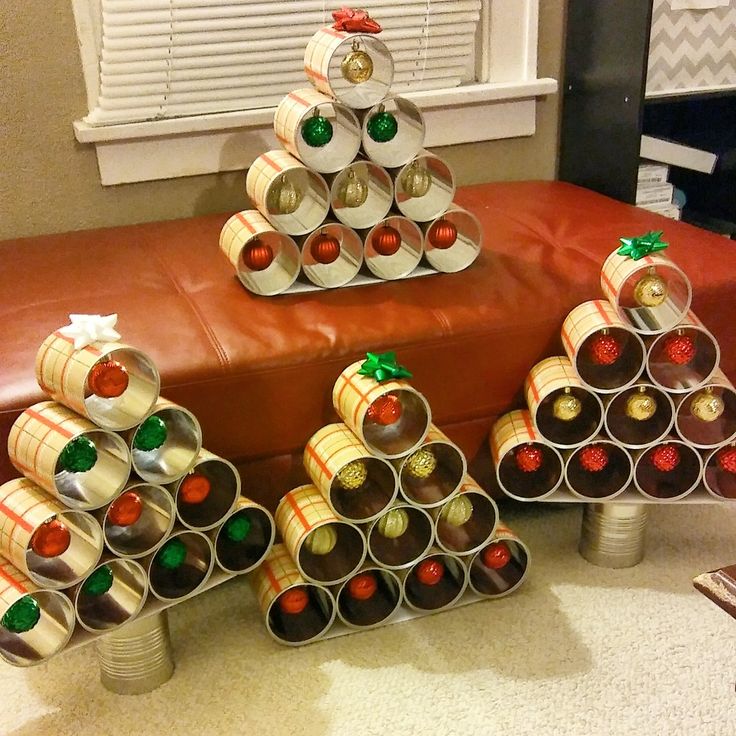 a christmas tree made out of cans is sitting on a bench in front of a window