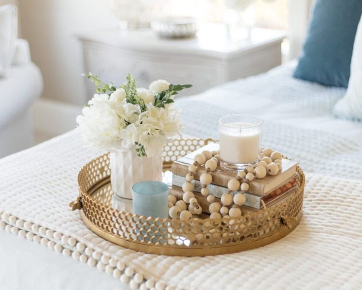 a tray with candles and flowers on it sitting on a bed next to a pillow