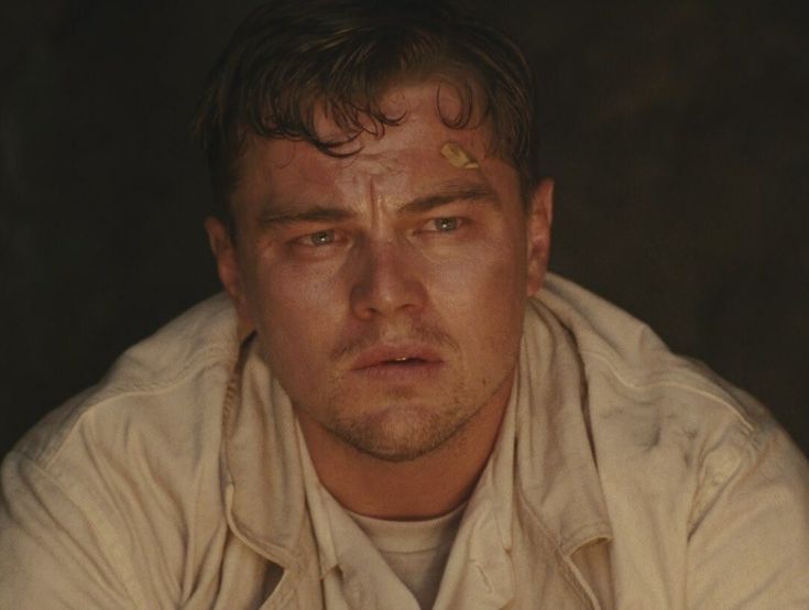 a close up of a person wearing a white shirt and looking at the camera with an evil look on his face