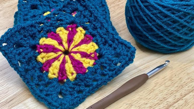 a crochet square with a ball of yarn next to it on a table