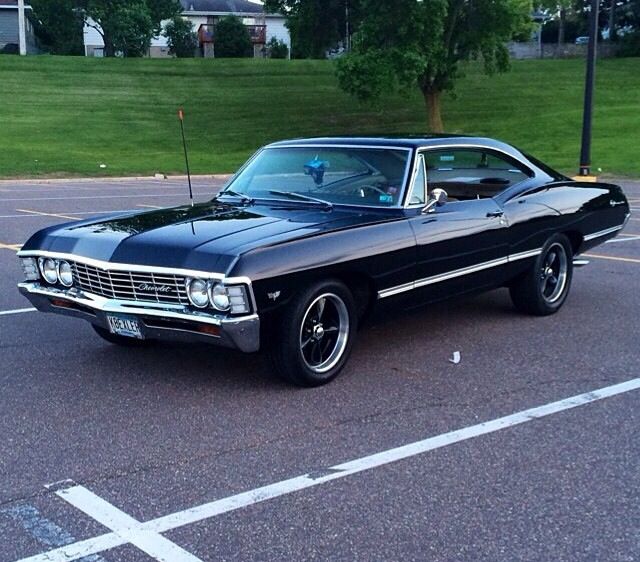 an old black car parked in a parking lot