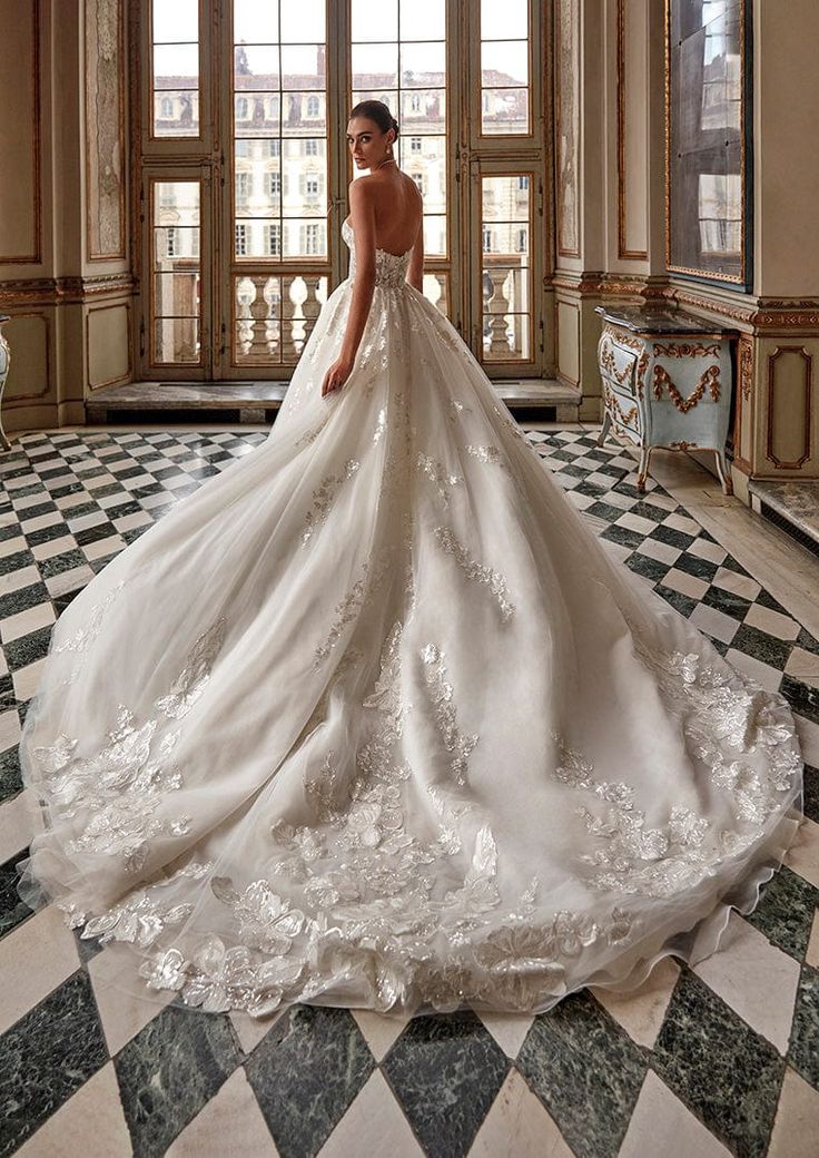 a woman in a white wedding dress standing on a checkered floor with windows behind her