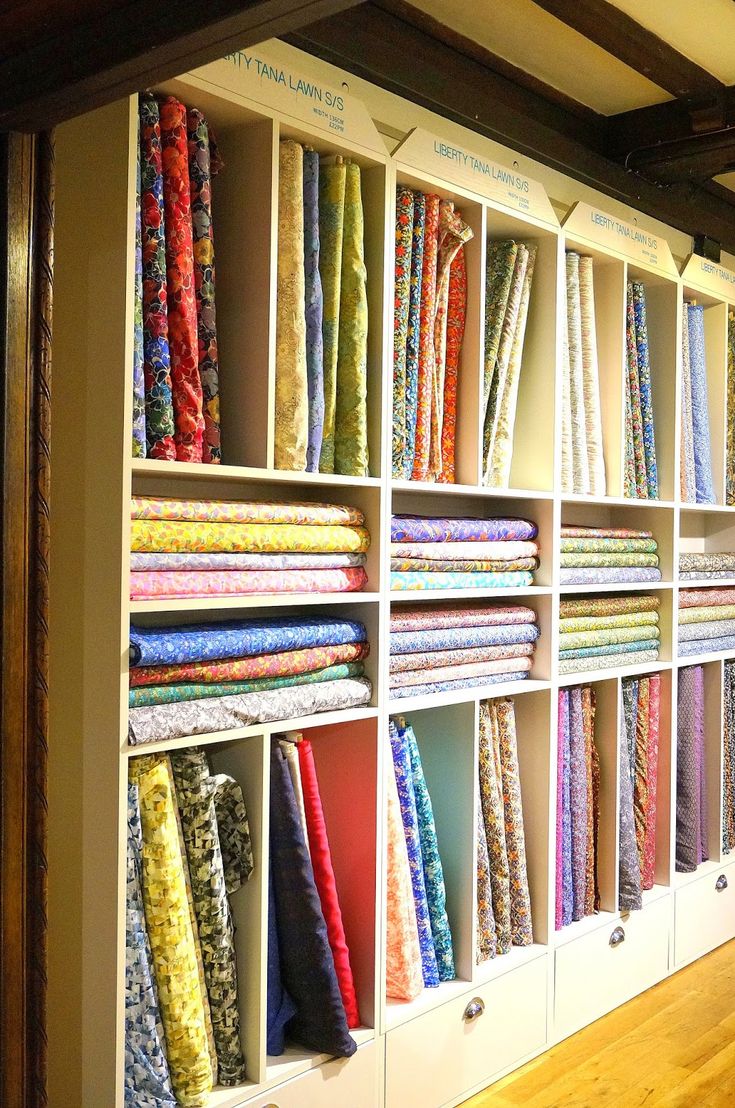 the shelves are filled with many different colored fabrics