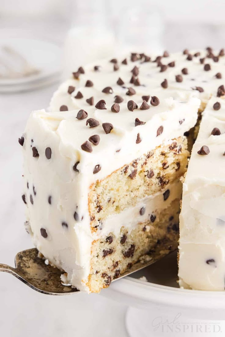 a cake with white frosting and chocolate chips on top is cut from the plate