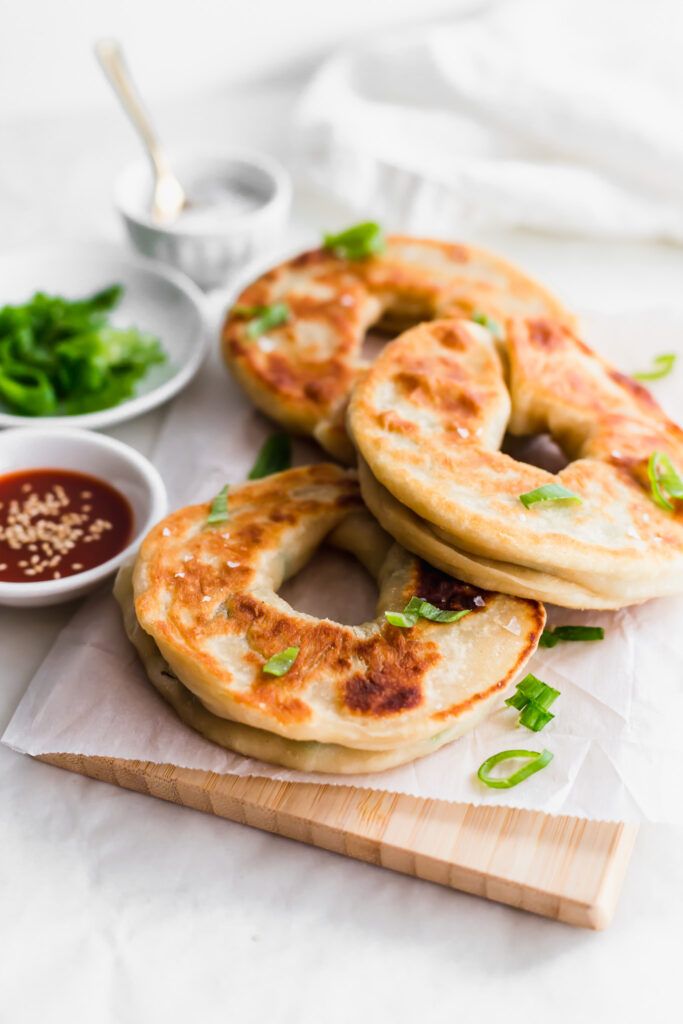 three bagels on a cutting board with dipping sauces