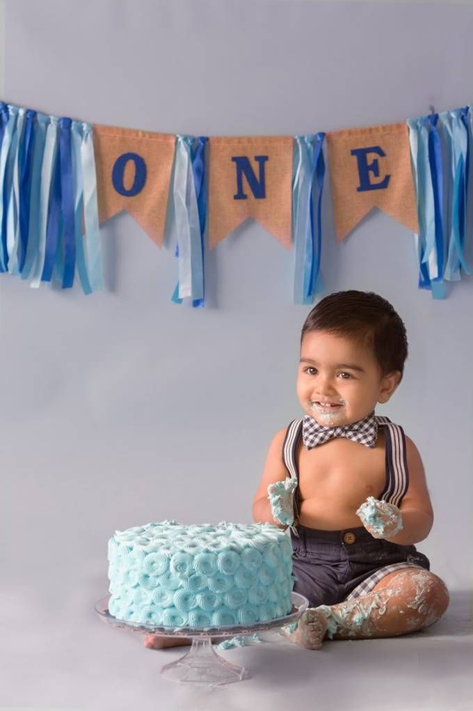 a baby boy sitting in front of a cake