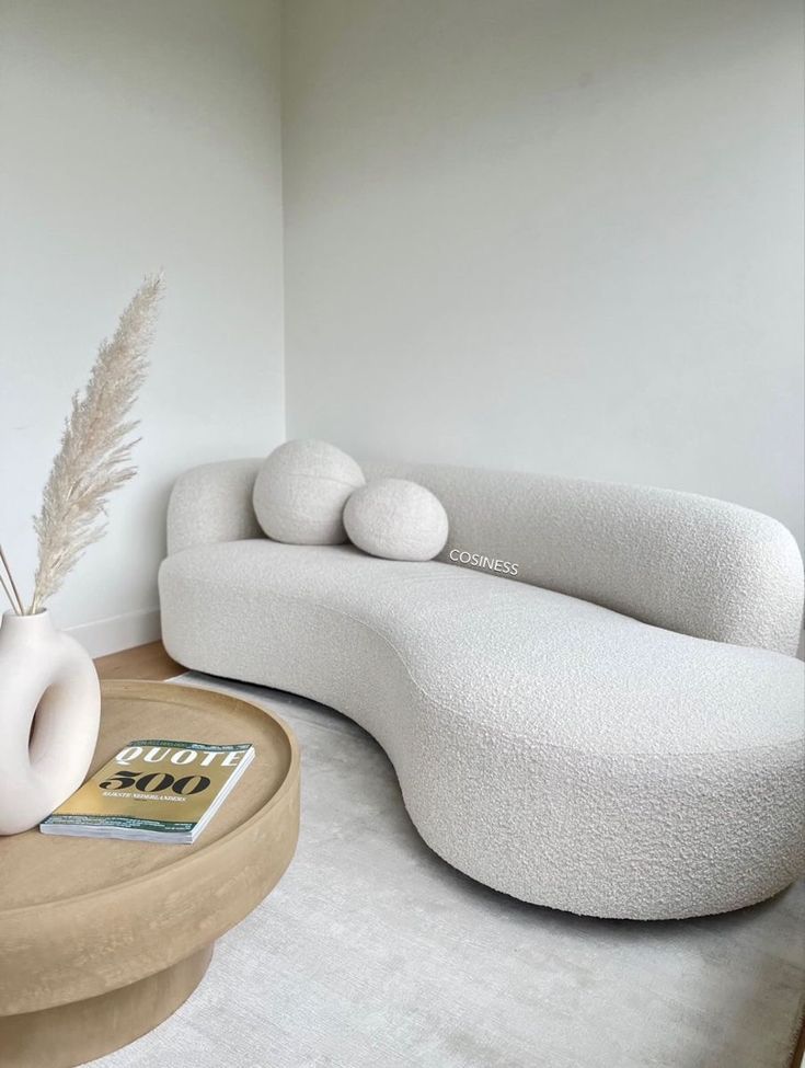 a modern living room with white furniture and large vases on top of the coffee table