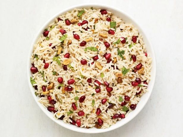 a bowl filled with rice and pomegranates on top of a table