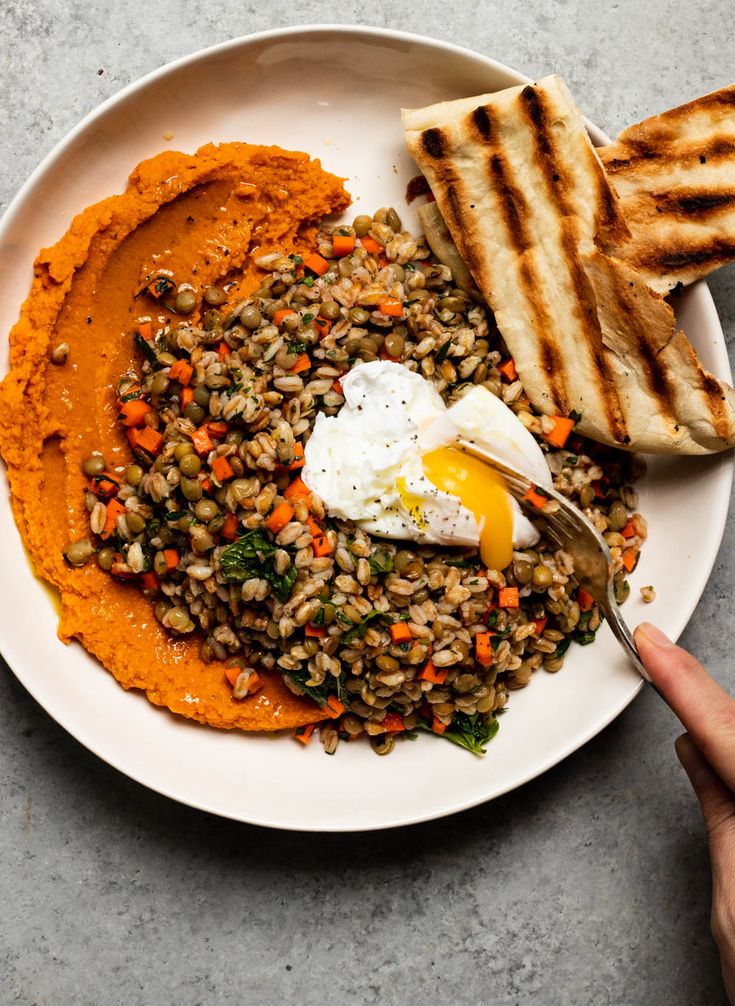 a white plate topped with lentils, toast and an egg