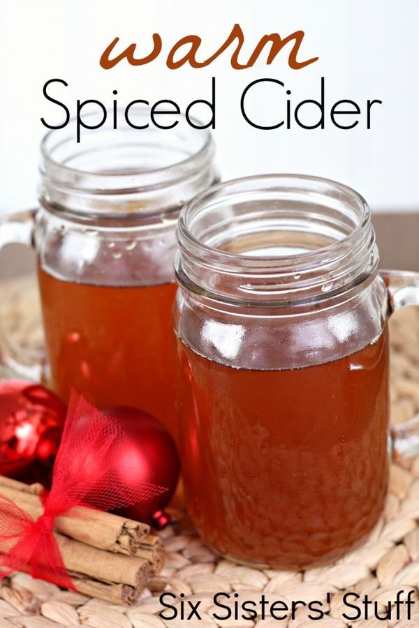 two mason jars filled with apple cider sitting on a table next to christmas ornaments