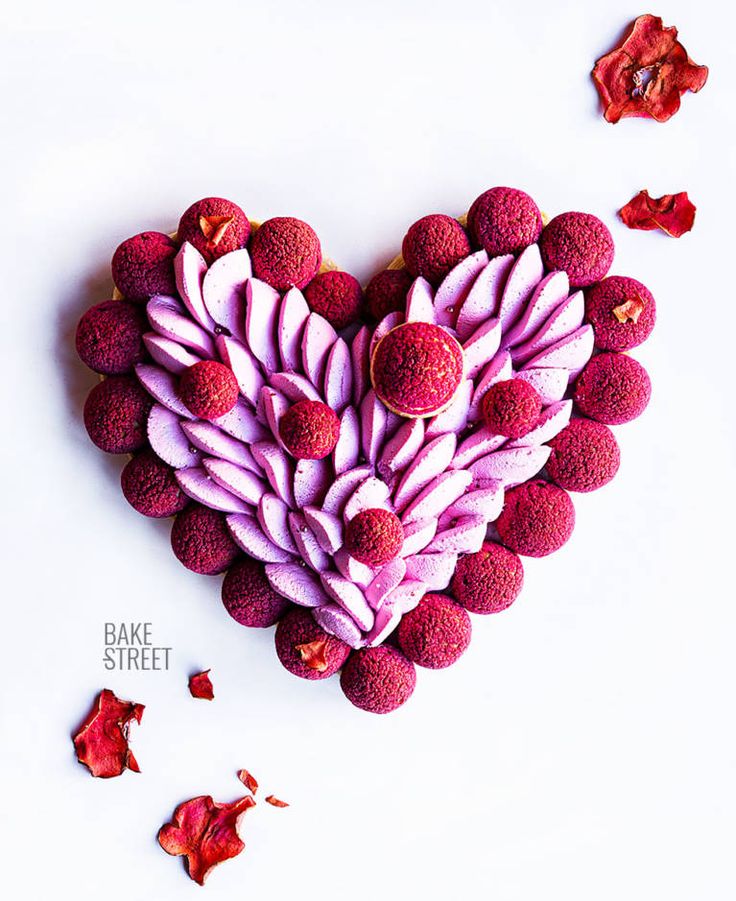 a heart shaped cake with pink frosting and rose petals