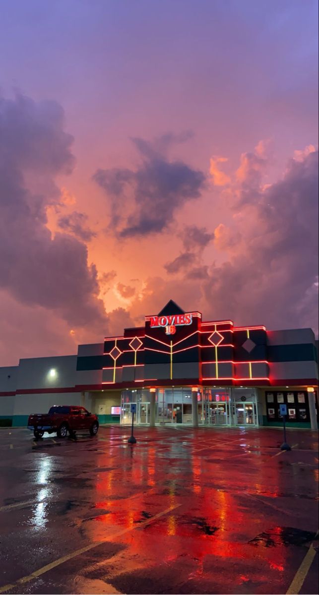 an empty parking lot with cars parked in front of it at sunset or sunrise time