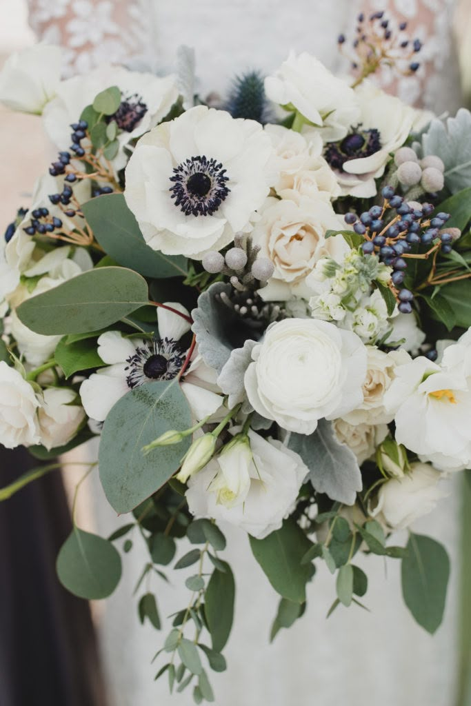 a bridal holding a bouquet of white flowers and greenery