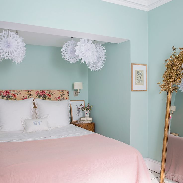 a bedroom with blue walls and pink bedspread on the bed is decorated with paper flowers