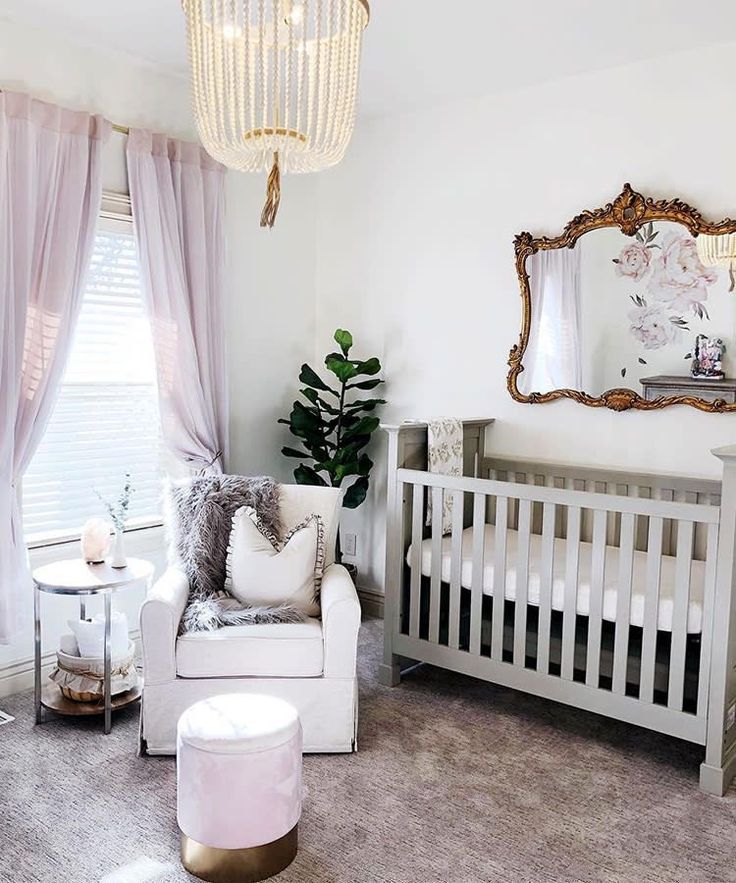 a baby's room with a white crib, chair and mirror on the wall