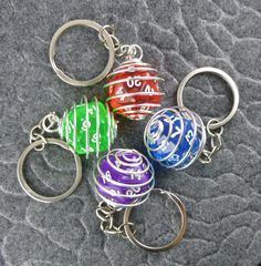 four different colored key chains with numbers and symbols on them sitting on a gray surface